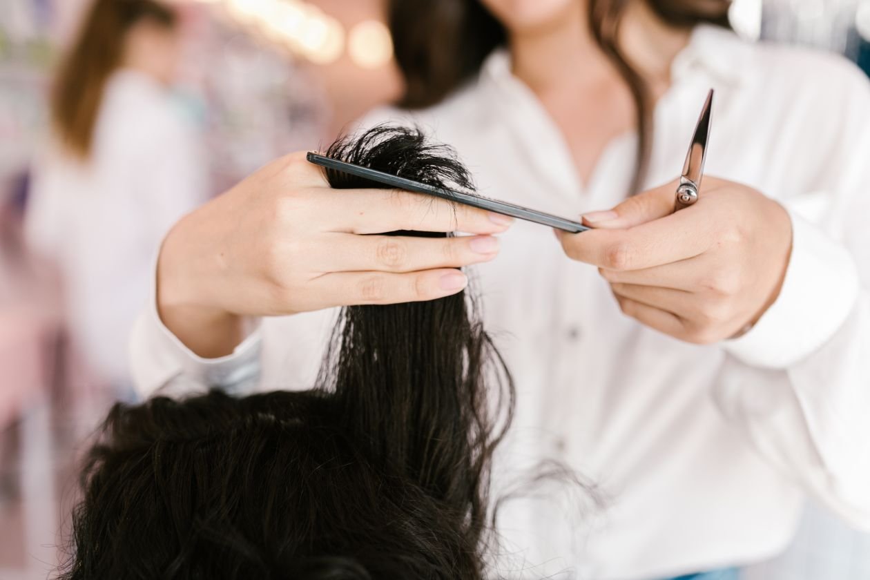 Hairdresser cutting layers with scissors and comb in a salon